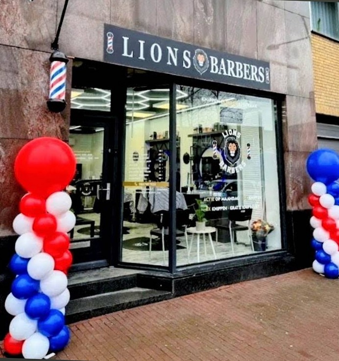 De gevel van Lions Barbers aan de Hoofdstraat, met barberpaal en rood-wit-blauwe ballonnen op de openingsdag